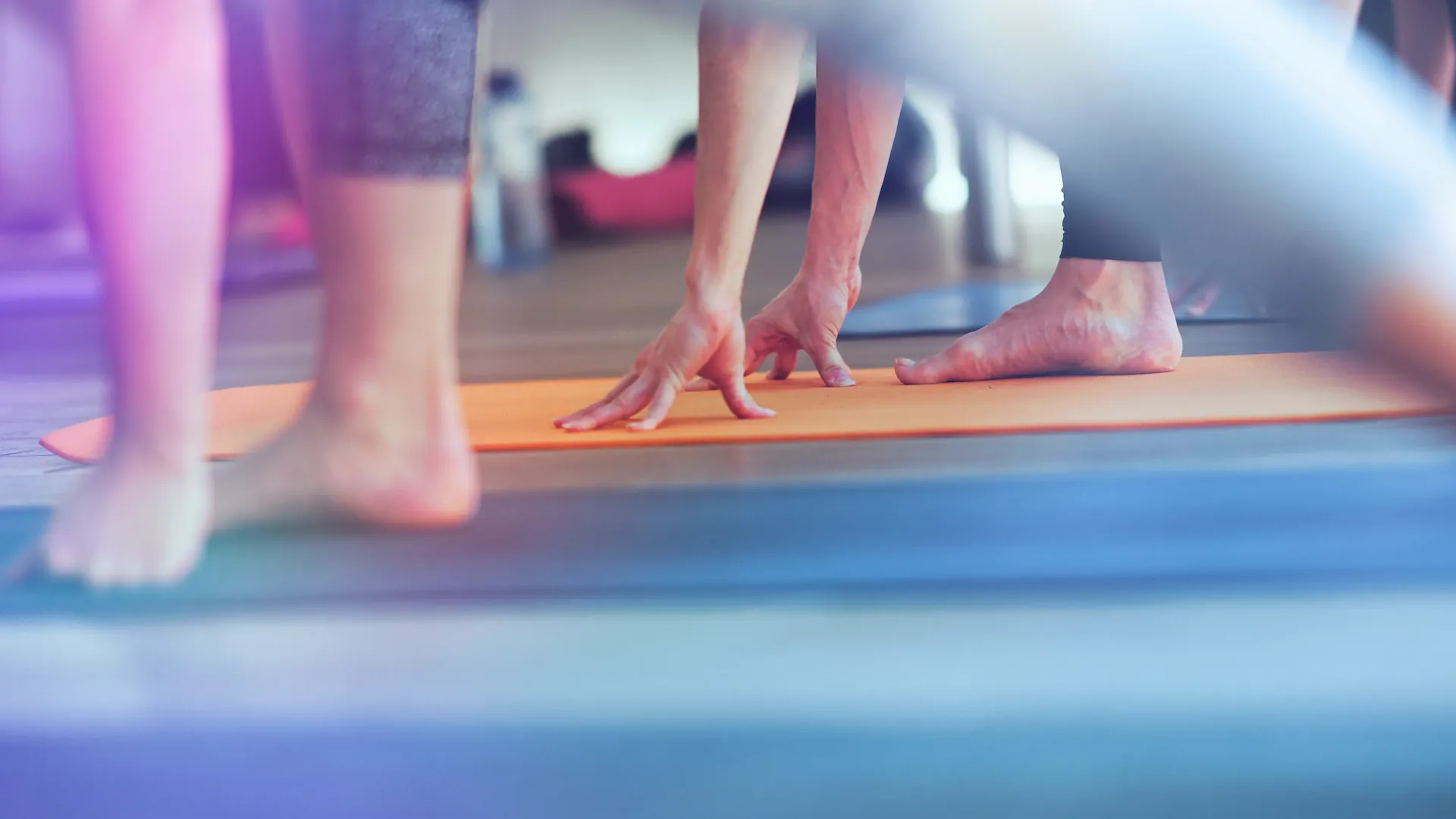 Nahaufnahme Fuesse und Haende auf oranger Yogamatte