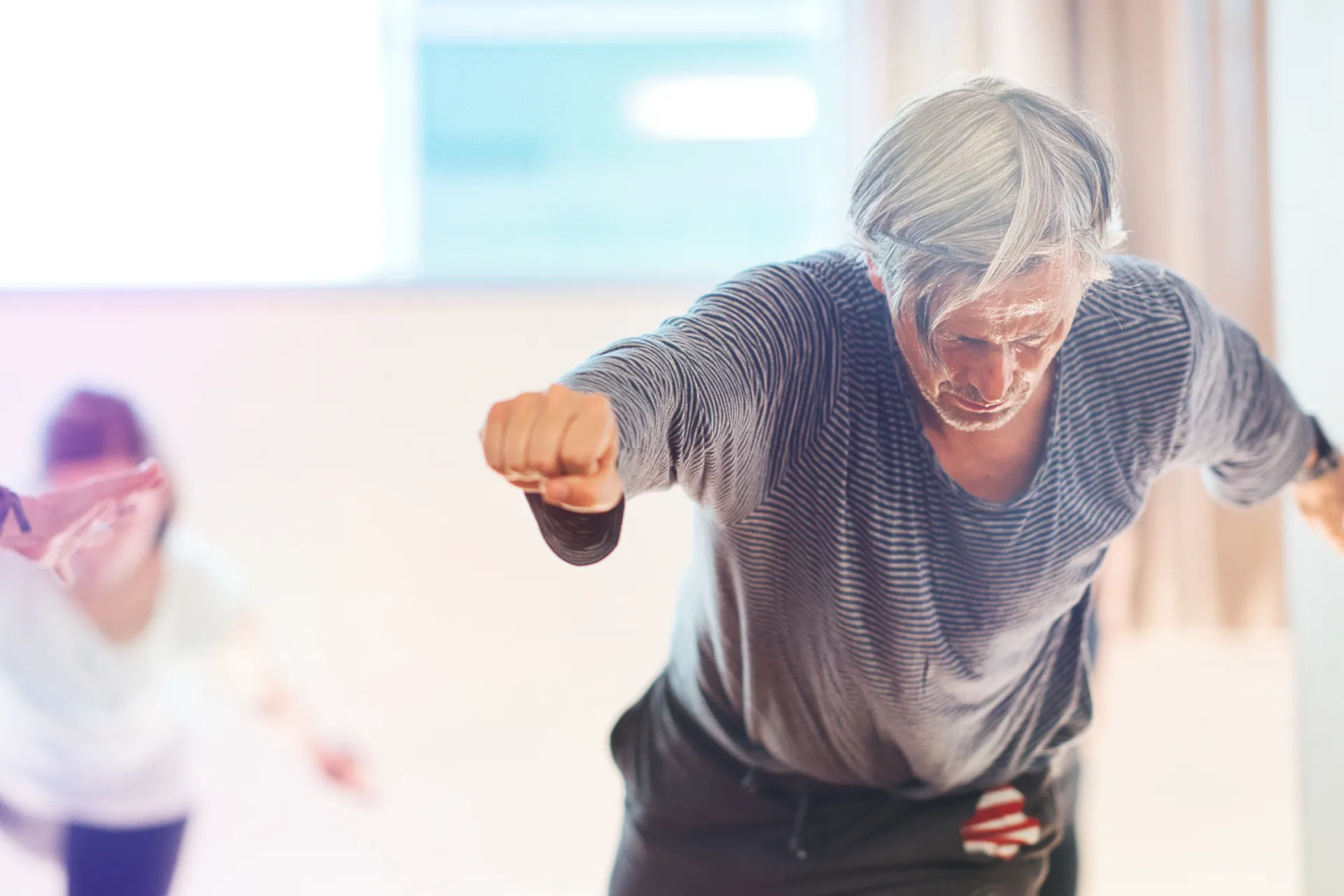 Aelterer Mann im gestreiften Shirt, dynamische Boxbewegung
