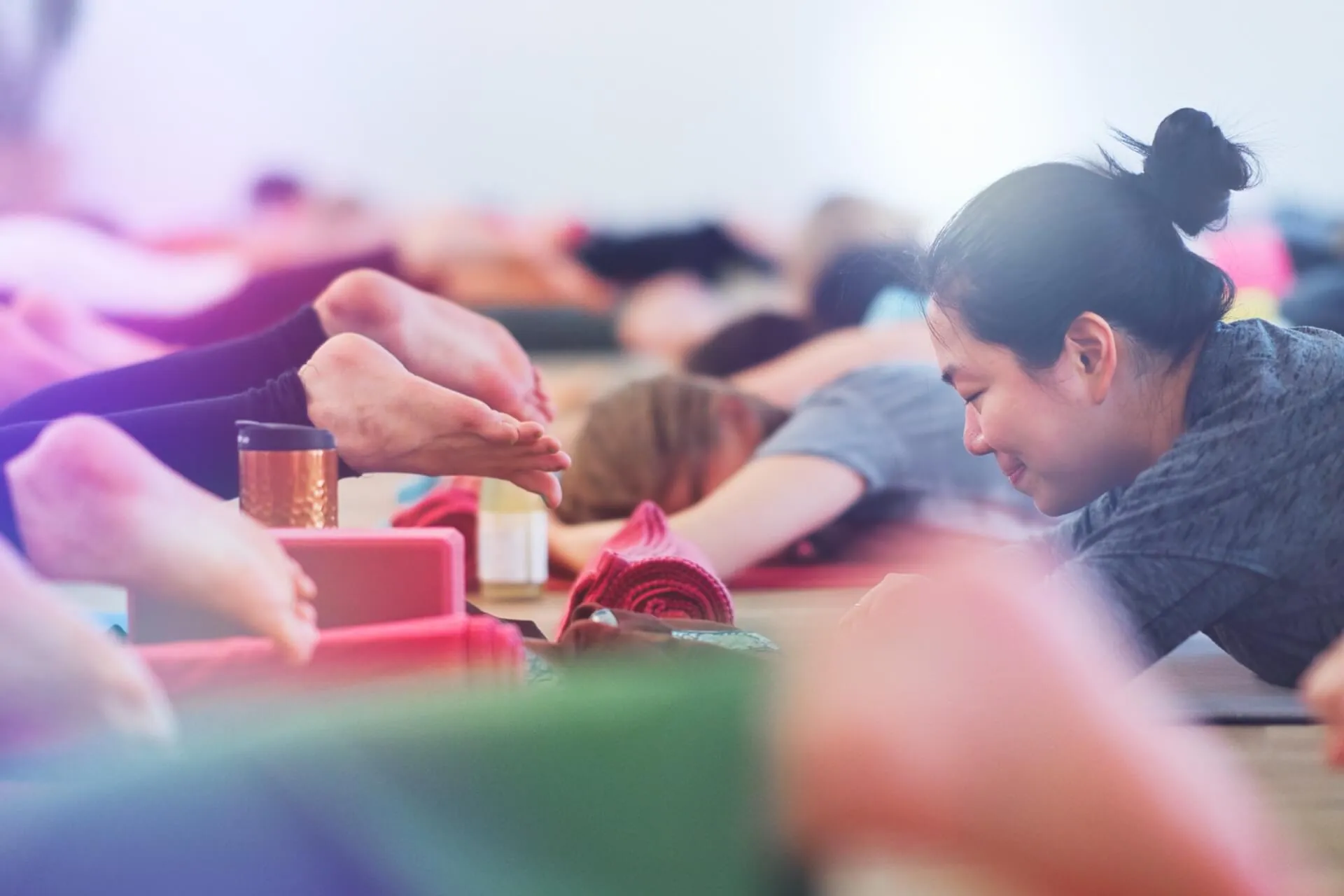 Frau mit Dutt in Vorwaertsbeuge, Props und Kupferbecher sichtbar