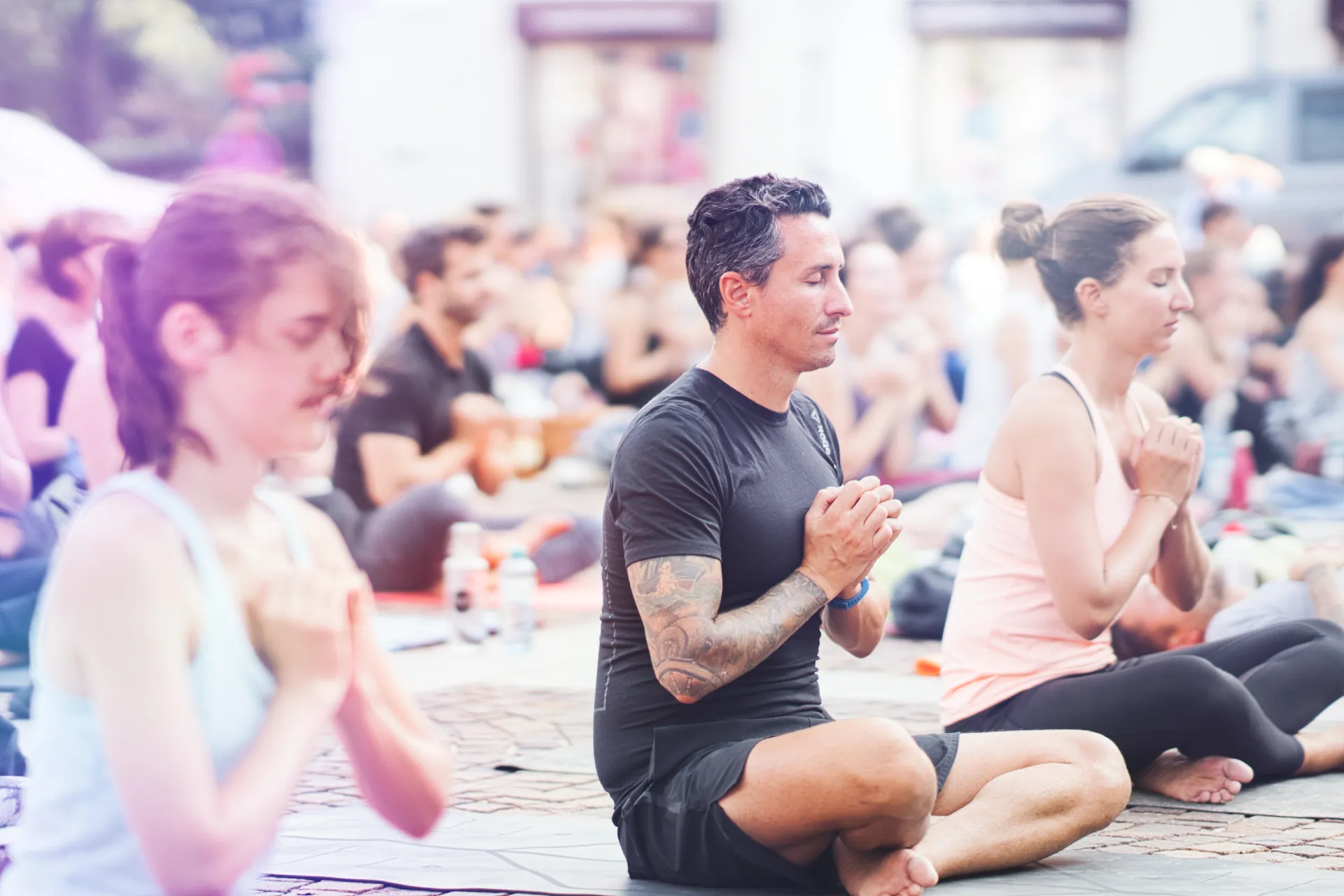 Sitzende Meditation draussen, Mann mit Tattoos, Haende in Gebetshaltung