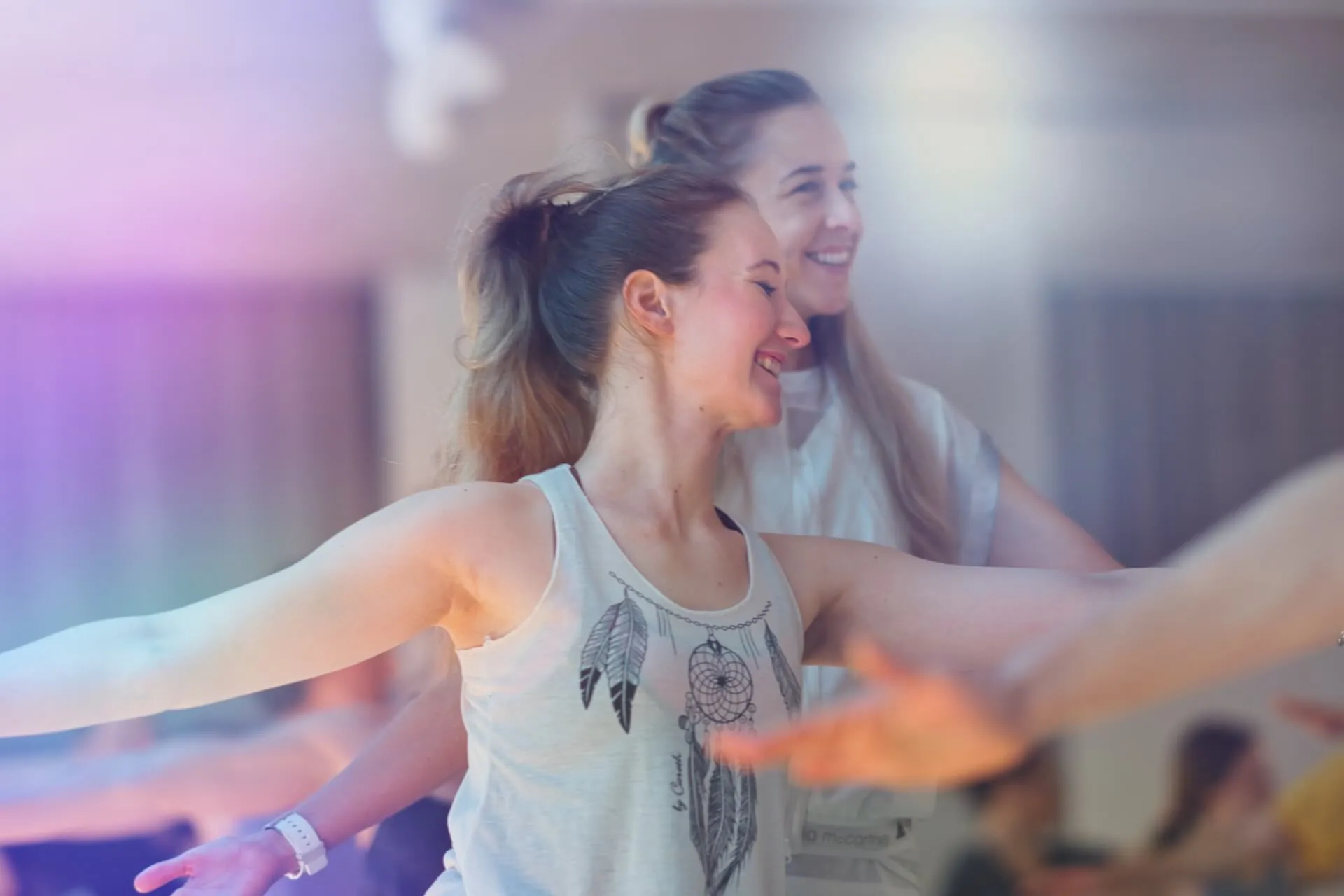Zwei junge Frauen lachen mit ausgestreckten Armen im Studio
